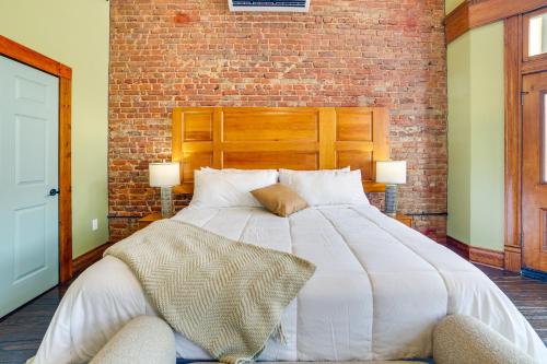 a large white bed in a room with a brick wall at Studio with Private Balcony in Downtown Marshall! in Marshall