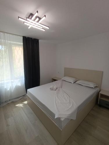 a bedroom with a large white bed with a chandelier at Zlata Bucovina Apartment in Suceava