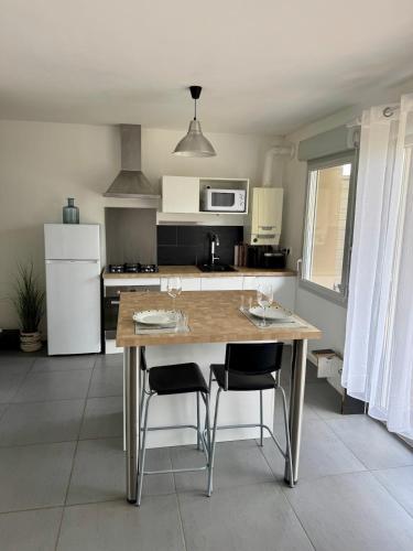 une cuisine avec une table en bois et deux chaises dans l'établissement Modern garden apartment, à Labenne