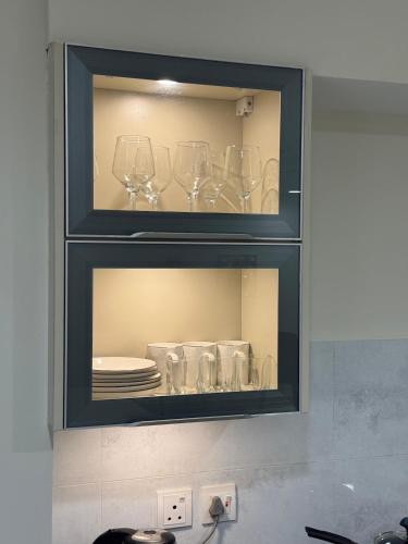 un mobiletto con dentro bicchieri da vino e piatti di Cozy Studio Apartment a Lahore