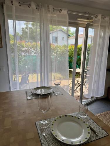 una mesa con un plato y dos copas de vino. en Modern garden apartment, en Labenne
