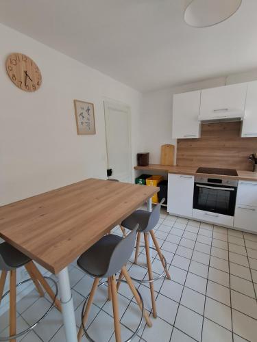 une cuisine avec une table en bois et deux chaises dans l'établissement Savannah - La maison des pins, à Mimizan-Plage