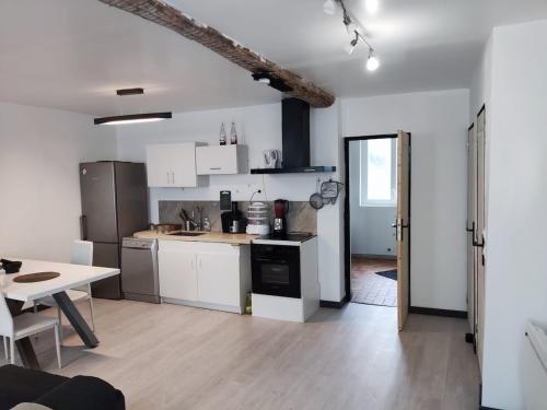una cocina con armarios blancos y una mesa en una habitación en 2 pièces Ecueillé, 20mn ZooBeauval, en Écueillé