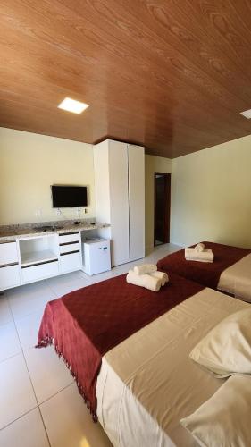 a bedroom with two beds and a flat screen tv at Linda casa com excelente localização em Boipeba in Ilha de Boipeba