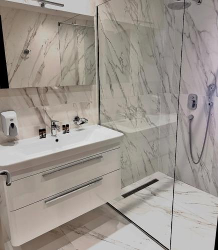 a white bathroom with a sink and a shower at Apartment Deluxe Gold in Rafailovici
