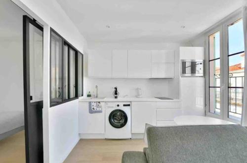 une cuisine avec des armoires blanches et une machine à laver dans l'établissement Cannes Croisette T2 new sublime, à Cannes
