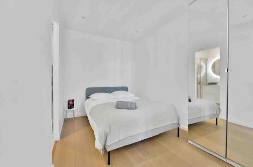 une chambre blanche avec un lit et un miroir dans l'établissement Cannes Croisette T2 new sublime, à Cannes