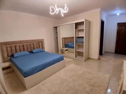a bedroom with a blue bed and a chandelier at شقة للايجار بالشيخ زايظ in Sheikh Zayed
