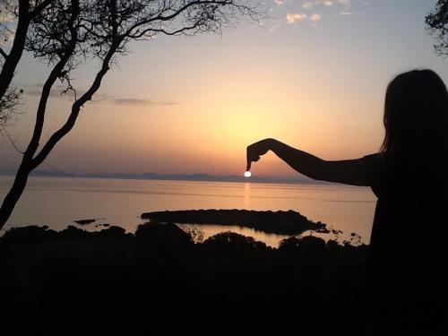 a woman is taking a picture of the sunset at Harmony Home in Pýrgos