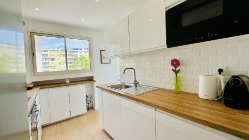 une cuisine avec des armoires blanches, un évier et une fenêtre dans l'établissement Arsenal, 4 chambres, Balcon, Parking, à Toulon