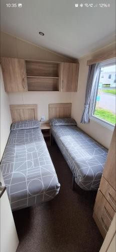 two beds in a small room with a window at The Shack - plot NB139 in Newquay Bay Resort