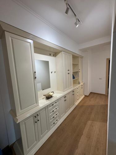 ein großes Badezimmer mit weißen Schränken und einem großen Spiegel in der Unterkunft Prime Apartment in Tirana