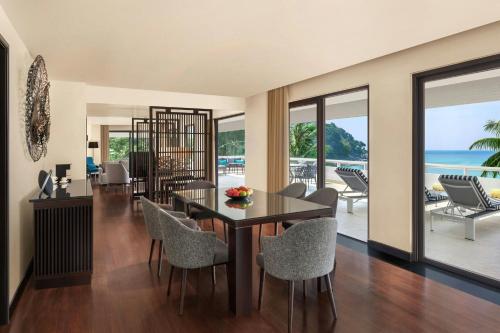 a dining room with a table and chairs and the ocean at Le Meridien Phuket Beach Resort in Karon Beach