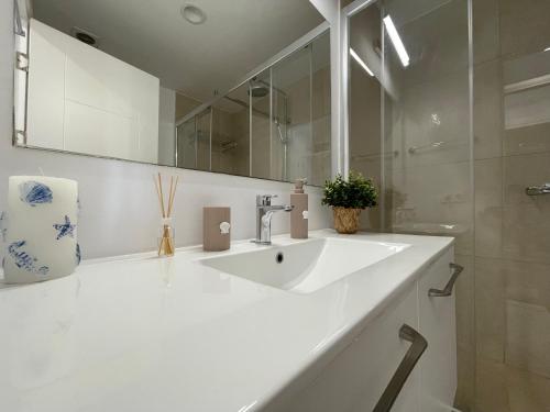 Un baño blanco con lavabo y espejo. en ROCA Seaview Apartments, en 23 August