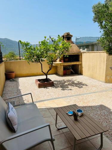 un patio con un banco, una mesa y un árbol en Casa Camilla, en Villasimius