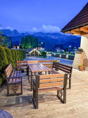 a group of wooden benches and tables on a deck at Willa Chrycówka - Jacuzzi, Basen, Sauna in Kościelisko