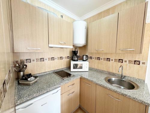 Una pequeña cocina con gabinetes de madera y un fregadero. en Ronda Suites A&N Marte, en Ronda