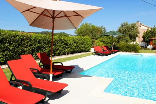 a pool with red chairs and an umbrella next to a pool at Casa do Sol - Turismo Rural - Nazaré Alcobaça in Cos