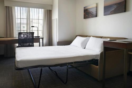 a bed in a hotel room with a desk and a chair at Residence Inn San Diego Del Mar in San Diego