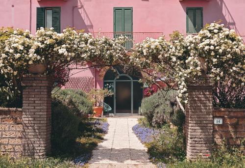 an archway with flowers in front of a pink house at La Casa dei Carrai in Pitigliano