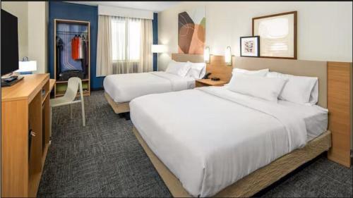 a hotel room with two beds and a desk at Spark by Hilton Glendive in Glendive