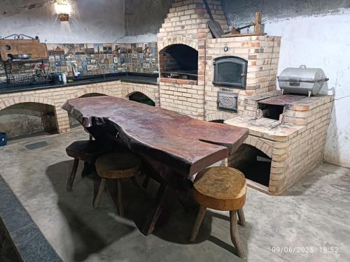 a kitchen with a wooden table and a brick oven at Sítio do patinhas in Nova Iguaçu