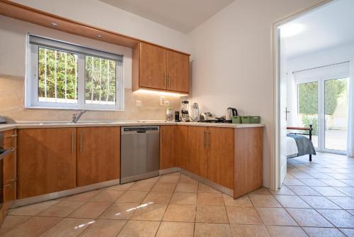 a kitchen with wooden cabinets and a sink and a window at G&A Family Home near the Beach by MΡS in Nea Makri