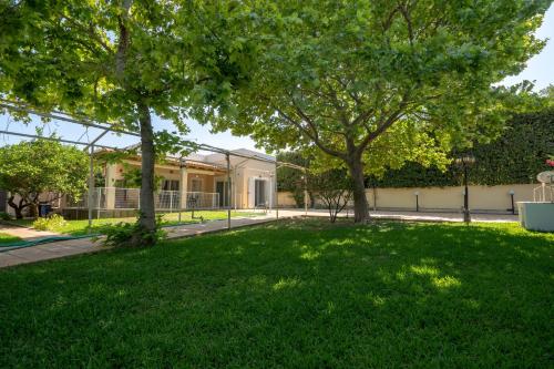 a green yard with trees in front of a building at G&A Family Home near the Beach by MΡS in Nea Makri