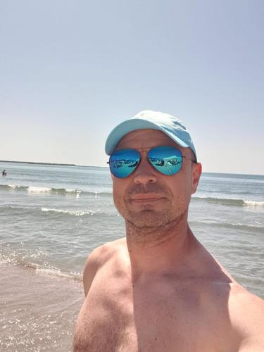 a man wearing sunglasses and a hat on the beach at Garsoniera in Vila Campus Constanta - New Building! in Constanţa