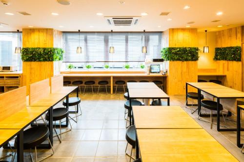 a restaurant with tables and chairs and plants at SUPERHOTEL Matsumoto Oshiroguchi in Matsumoto