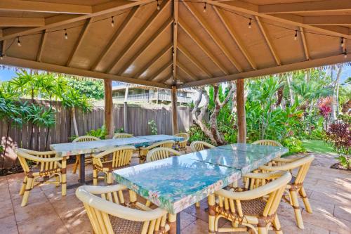 a patio with tables and chairs under a wooden umbrella at The Mauian Hotel in Lahaina