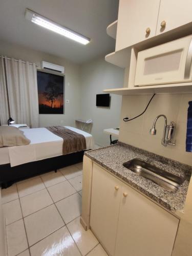 a room with a bed and a kitchen with a sink at Loft 220 Ar Cond Wi-fi com Box TV filmes e séries in Niterói