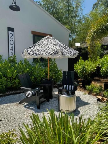 a patio with two chairs and an umbrella at Walk to Best Eats and Shops and Stay in Style in Fort Myers