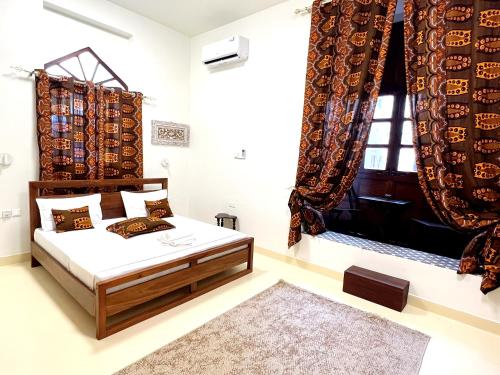 a bedroom with a bed and a window with curtains at Treasures of Zanzibar House in Zanzibar City