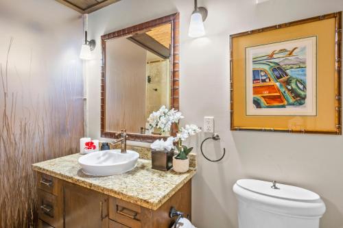 a bathroom with a sink and a toilet and a mirror at The Mauian Hotel in Lahaina
