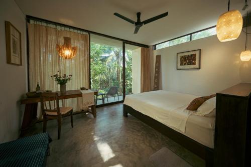 a bedroom with a bed and a desk and a window at Kyara Arthouse Villa in Thanh Ðông (1)