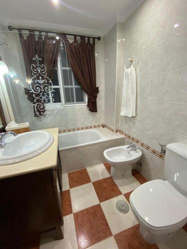 a bathroom with a toilet and a sink and a tub at Ohana in Sanlúcar de Barrameda