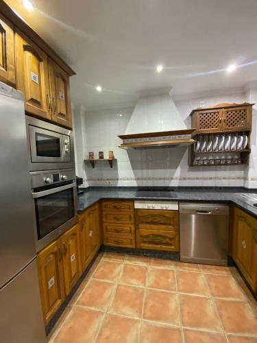 a kitchen with wooden cabinets and stainless steel appliances at Ohana in Sanlúcar de Barrameda