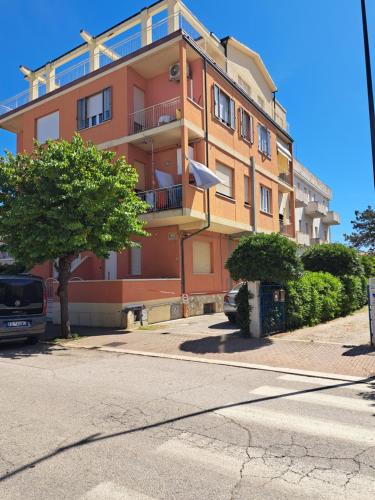 a tall orange building with a tree in front of it at Casa HAPPINESS vista mare, 50m dal mare in Marotta