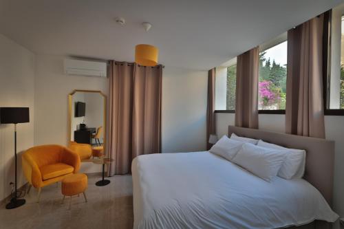 une chambre avec un lit blanc et une chaise jaune dans l'établissement Hôtel Villa Martini, à Ajaccio