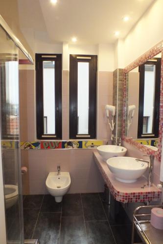 a bathroom with two sinks and two mirrors at Atmos Luxe Navigli in Milan