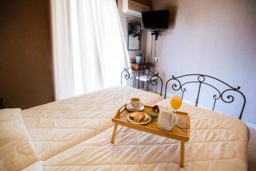 a bed with a table with a tray of food on it at Nepheli Hotel in Kastrosikia