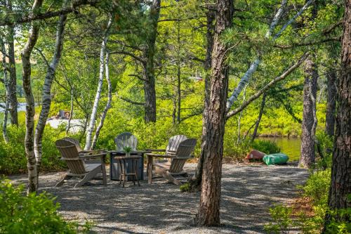 a picnic table and chairs in the woods at Lakers Pointe by AvantStay Lakefront Private Peninsula Hot Tub Game Room in Long Pond