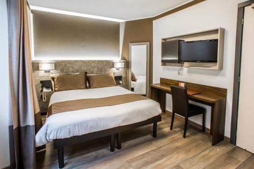 a bedroom with a bed and a desk and a tv at Hotel Ristorante Eurossola in Domodossola