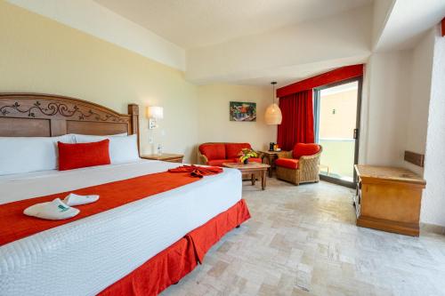 a bedroom with a large bed and a living room at Copacabana Beach Hotel Acapulco in Acapulco