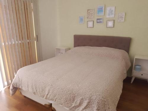una camera da letto con un letto con copriletto bianco e quadri appesi al muro di Casa con Jardín, Piscina y Vistas Increíbles en Potrero de los Funes a Potrero de los Funes