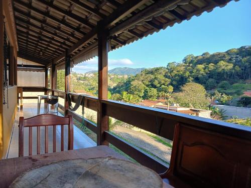 a view from the balcony of a house with a table and chairs at Toca do Dino - casa aconchegante com vista, lareira, piscina e área kids in Miguel Pereira