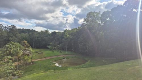 a view of a field with trees and a pond at Pousada Lua chalé in Blumenau