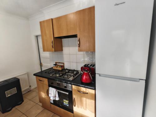 a kitchen with a stove top oven next to a refrigerator at Lovely Apartment With Private Garden & Parking in Borehamwood