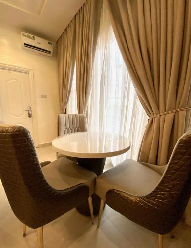 a table and chairs in a room with a window at Lucy and Jacobs Luxury Apartment in Port Harcourt